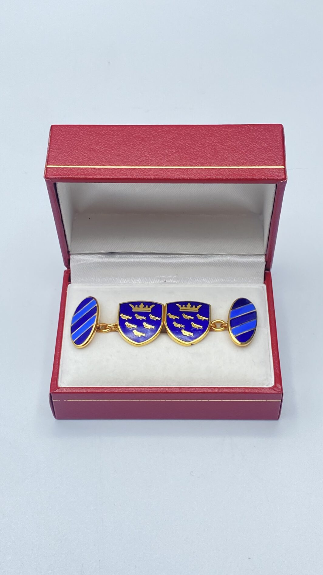PAIO DI GEMELLI IN METALLO DORATO E SMALTI, CON STEMMA DEL SUSSEX E CORONA ARALDICA. VINTAGE ANNI ‘50/‘60