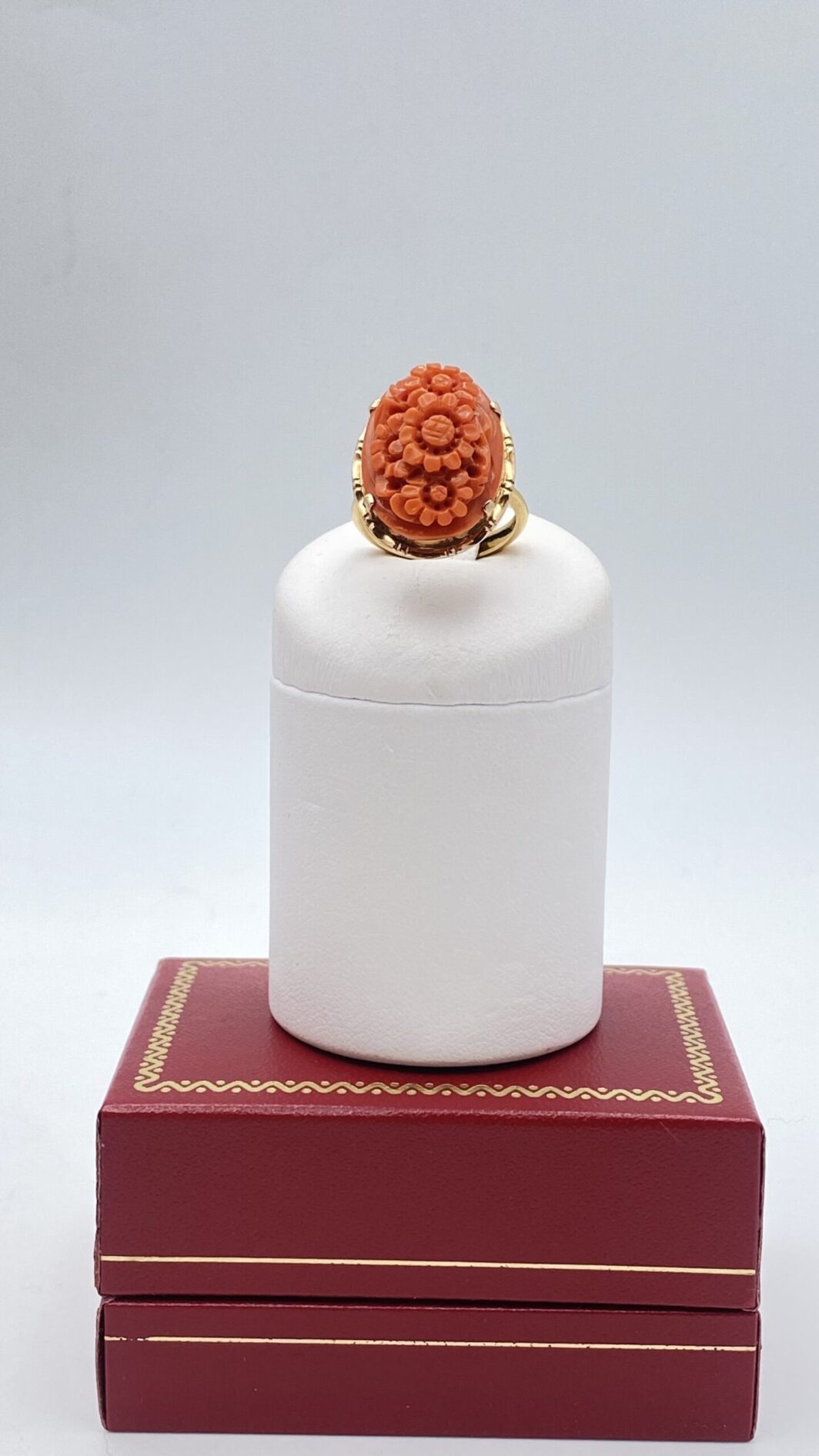 SPLENDIDO ANELLO FLOREALE IN CORALLO DI SCIACCA INTAGLIATO CON GERBERE E MONTATURA IN ORO 18KT. ITALIA, PRIMA METÀ DEL XX SECOLO.