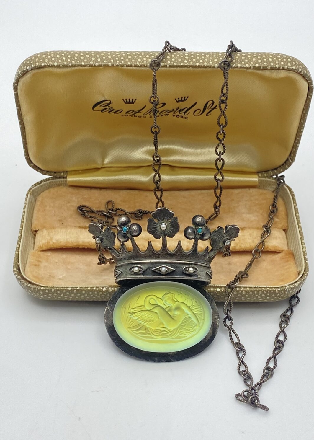 STRAORDINARIA COLLANA ART DECO, IN ARGENTO 925, CON PENDENTE A FORMA DI CORONA ORNATA DI TURCHESI E MICROPERLE, CARATTERIZZATO DA CRISTALLO SCOLPITO CON LA RAFFIGURAZIONE DEL MITO DI “GIOVE E LEDA”. INIZI XX sec.
