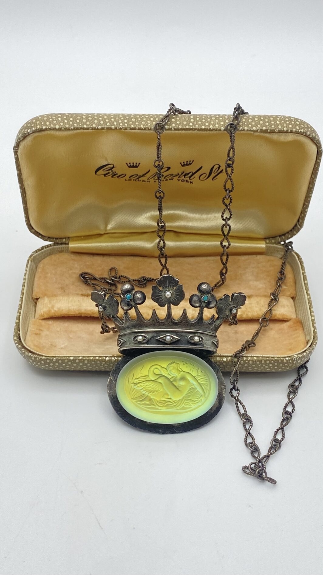 STRAORDINARIA COLLANA ART DECO, IN ARGENTO 925, CON PENDENTE A FORMA DI CORONA ORNATA DI TURCHESI E MICROPERLE, CARATTERIZZATO DA CRISTALLO SCOLPITO CON LA RAFFIGURAZIONE DEL MITO DI “GIOVE E LEDA”. INIZI XX sec.