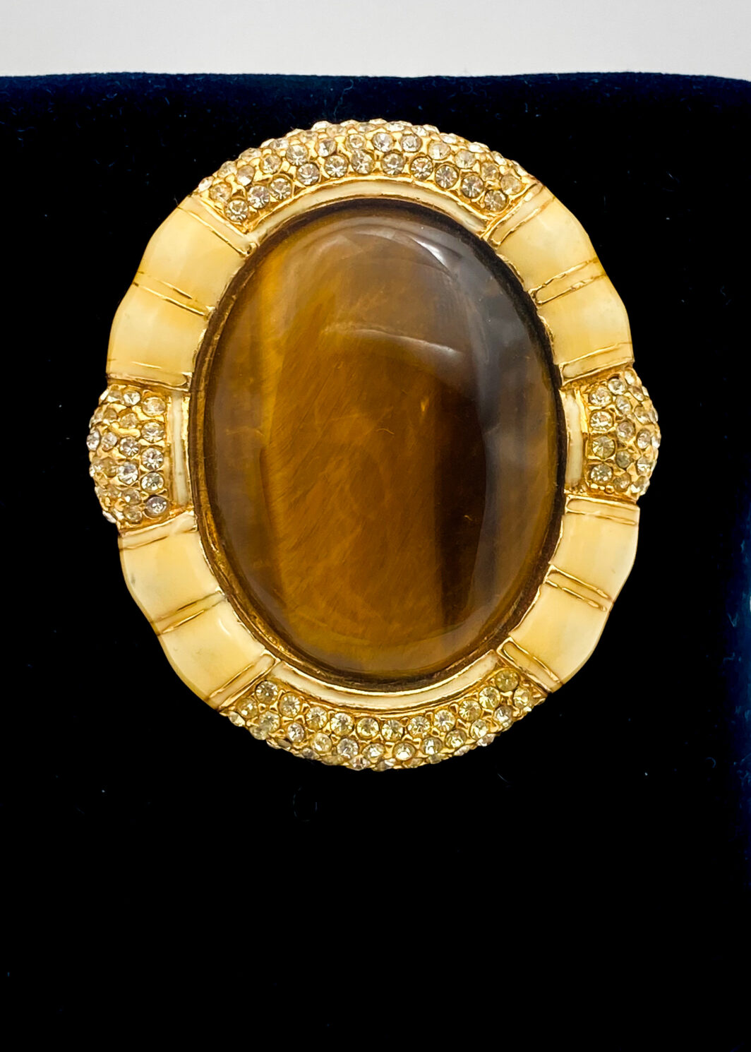 STRAORDINARIA SPILLA VINTAGE IN METALLO GOLDTONE, SMALTI, CRISTALLI DIAMONDLIKE E VERO CABOCHON DI PIETRA OCCHIO DI TIGRE. CREAZIONE DELLA CELEBRE MAISON DI BIGIOTTERIA AMERICANA “CINER”, EPOCA ANNI ‘30/‘40