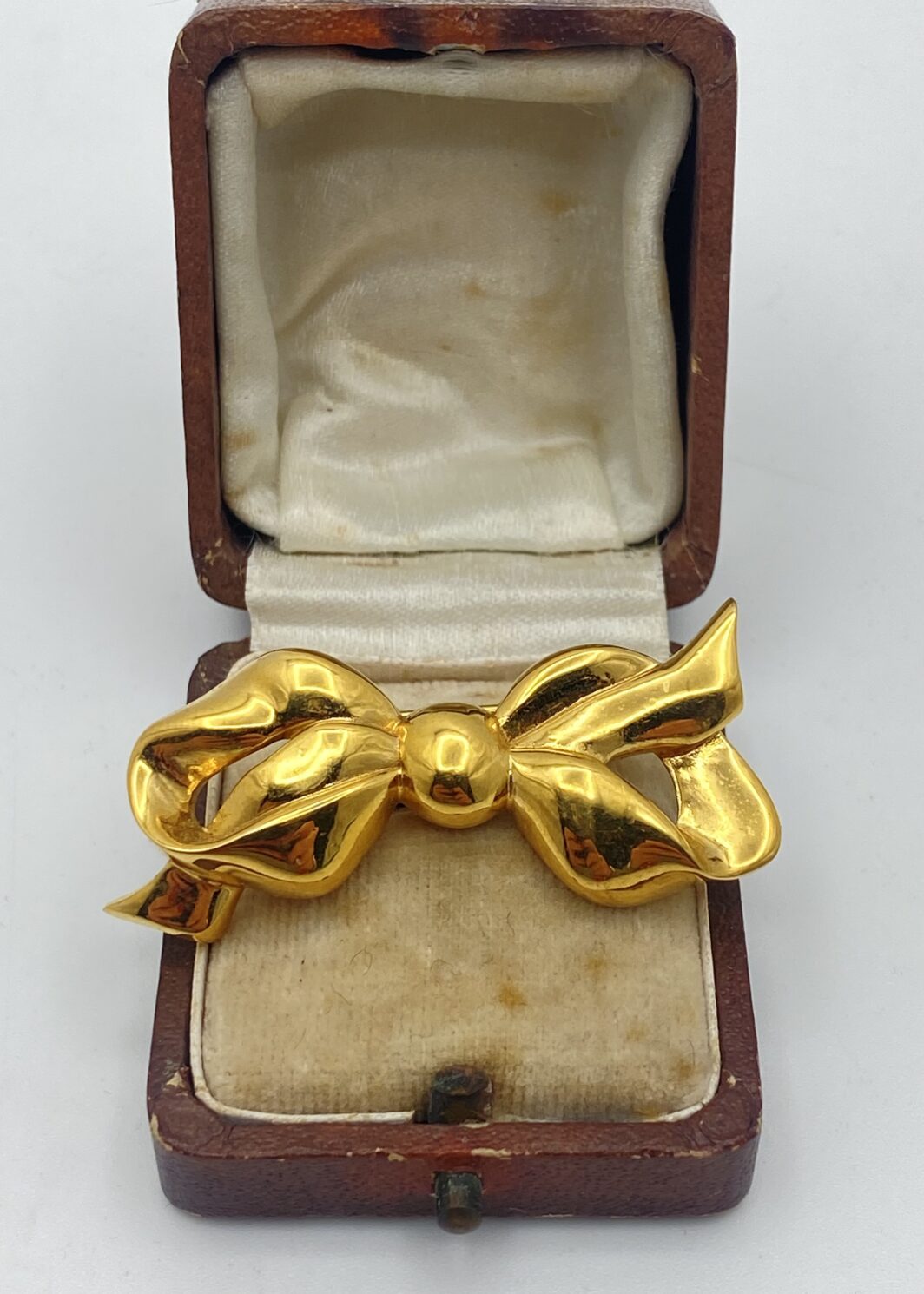ELEGANZA SENZA TEMPO. SPILLA VINTAGE ANNI’50/‘60, A FORMA DI NODO D’AMORE FIRMATA “NINA RICCI”, IN METALLO GOLDTONE.