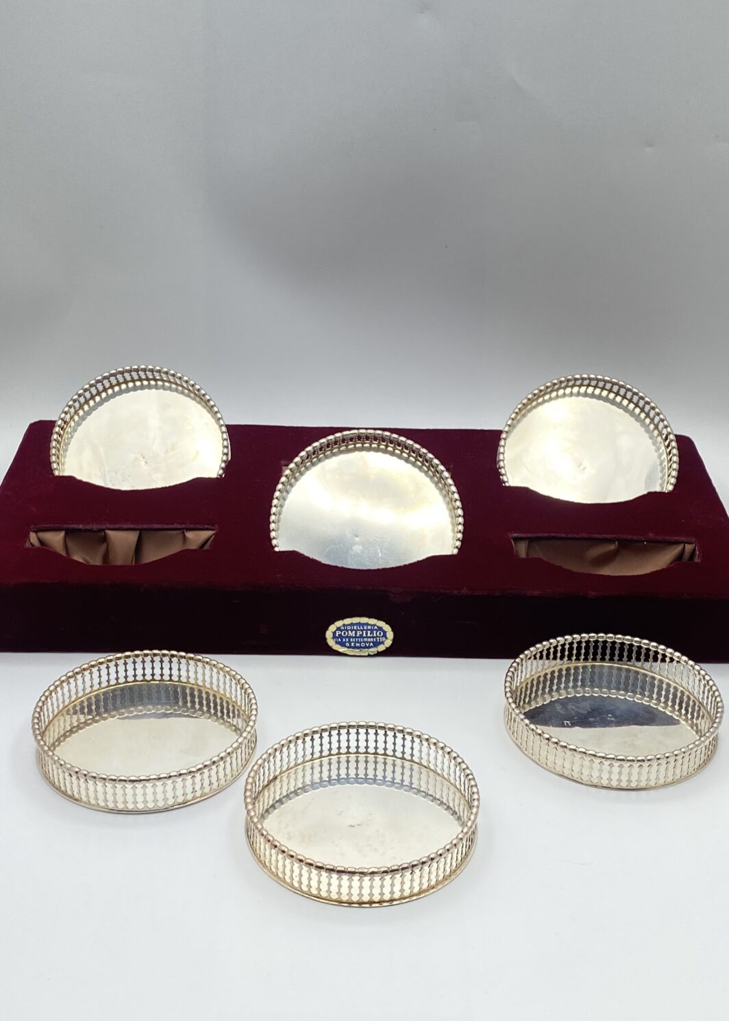 ELEGANTISSIMO SET DI SEI SOTTOBICCHIERI IN ARGENTO FINEMENTE SAGOMATO E TRAFORATO, CON CUSTODIA ORIGINALE RIVESTITA IN VELLUTO. OREFICERIA POMPILIO, GENOVA, PRIMA METÀ DEL XX sec.