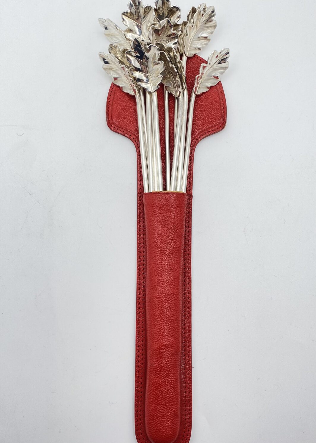STRAORDINARIO E RARO SET DI 12 CANNUCCE DA COCKTAIL, CON CUCCHIAINI A FOGLIA DI QUERCIA. OPERA DELLA CELEBRE ARGENTERIA CLEMENTI DI BOLOGNA, ASSORBITA DA BUCCELLATI. ITALIA, VINTAGE ANNI ‘60/‘70.