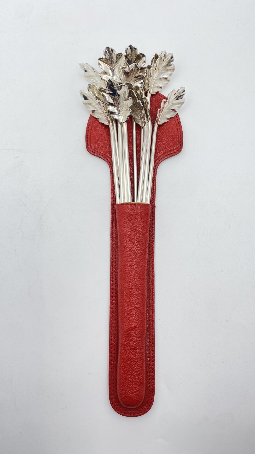 STRAORDINARIO E RARO SET DI 12 CANNUCCE DA COCKTAIL, CON CUCCHIAINI A FOGLIA DI QUERCIA. OPERA DELLA CELEBRE ARGENTERIA CLEMENTI DI BOLOGNA, ASSORBITA DA BUCCELLATI. ITALIA, VINTAGE ANNI ‘60/‘70.