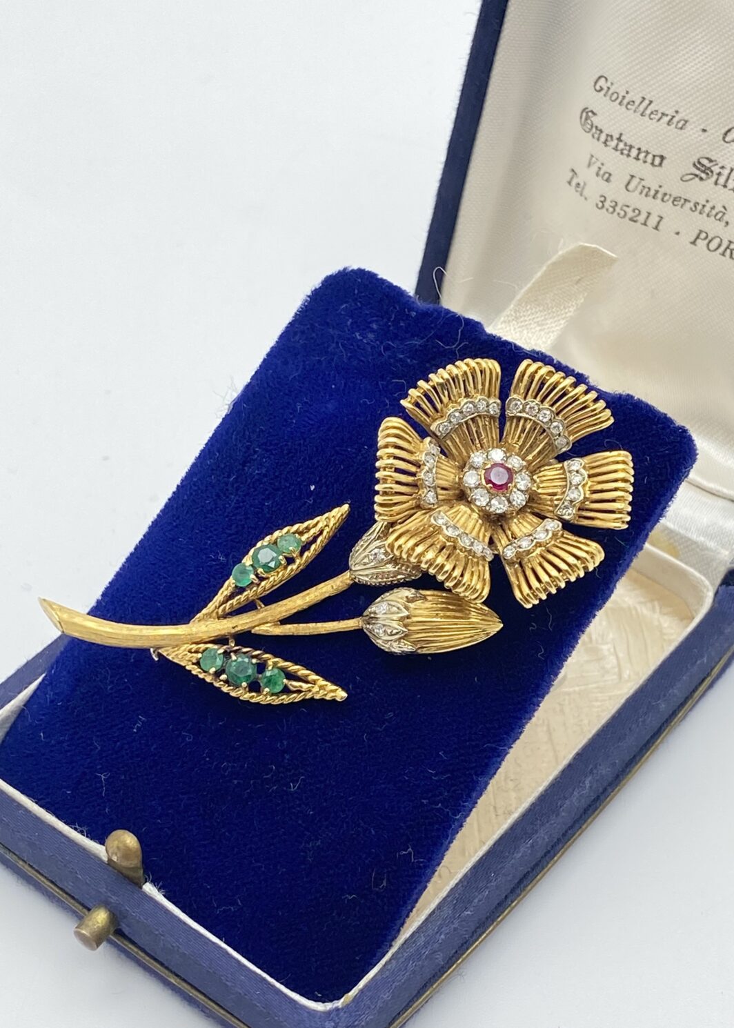 MERAVIGLIOSA SPILLA FLOREALE IN ORO 18KT, CON 0,20CT DI BRILLANTI E 0,30CT DI SMERALDI E RUBINO CENTRALE. ITALIA, ANNI ‘50.