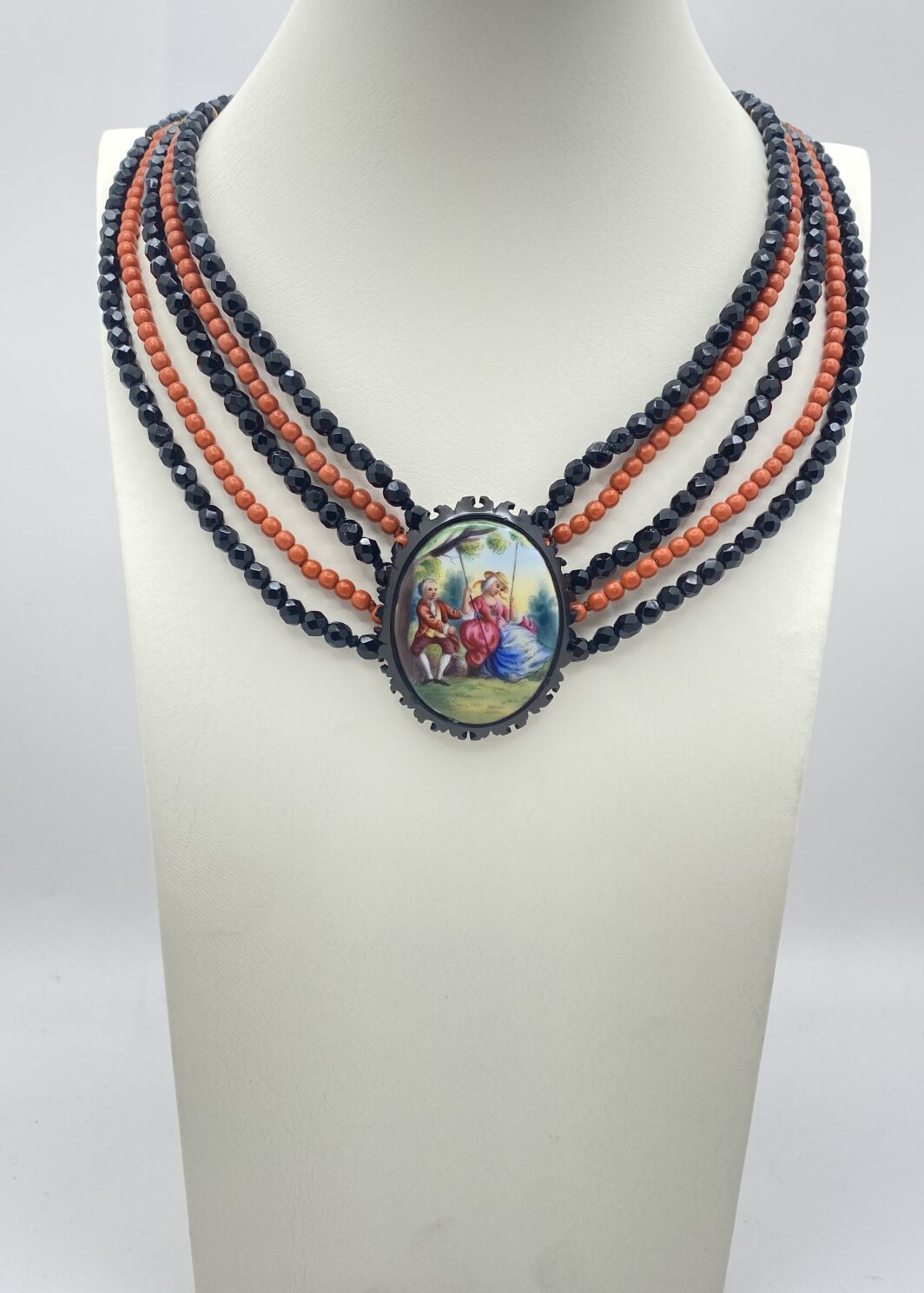 COLLANA VITTORIANA DA SOGNO A CINQUE FILI IN VETRO NERO SFACCETTATO E IN SIMIL CORALLO, CON SPLENDIDA PLACCA IN PORCELLANA FINEMENTE SMALTATA CON SCENA GALANTE,  CON CORNICE IN GIAIETTO: UN CAPOLAVORO D’EPOCA INIMITABILE.