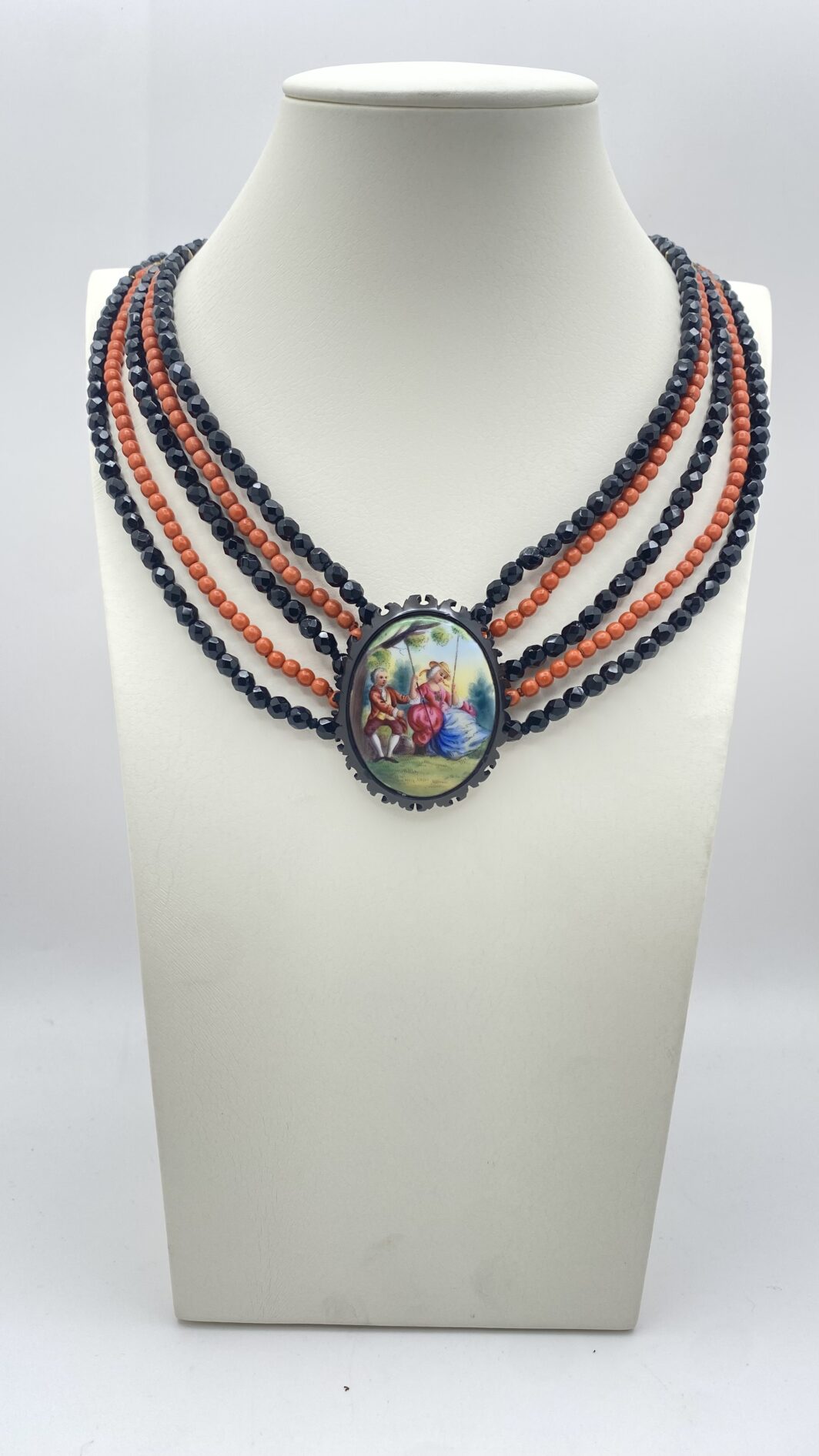 COLLANA VITTORIANA DA SOGNO A CINQUE FILI IN VETRO NERO SFACCETTATO E IN SIMIL CORALLO, CON SPLENDIDA PLACCA IN PORCELLANA FINEMENTE SMALTATA CON SCENA GALANTE,  CON CORNICE IN GIAIETTO: UN CAPOLAVORO D’EPOCA INIMITABILE.
