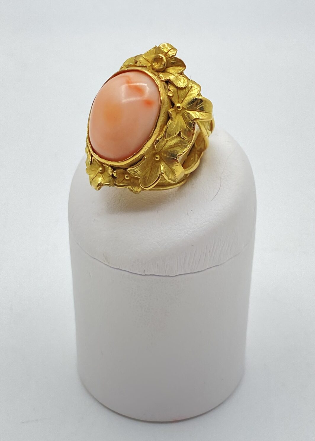 CAPOLAVORO VINTAGE ANNI ’80. MAGNIFICO ANELLO CON CORALLO ROSA CENTRALE, IN ORO 18KT, ESEGUITO CON LA TECNICA DELLA FUSIONE A CERA PERSA, DECORATO A MOTIVI FLOREALI, NELLO STILE BUCCELLATI.