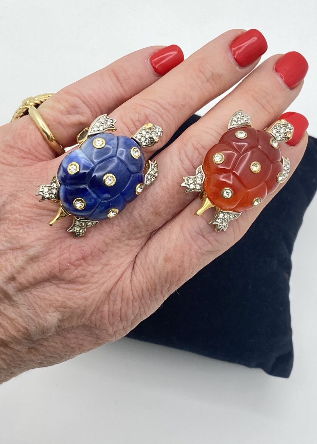 MAGNIFICO PAIO DI SPILLE IN METALLO GOLDTONE FINEMENTE SAGOMATO A FORMA DI TARTARUGHINE, CON CARAPACE IN LUCITE BLU ZAFFIRO E ROSSO CORNIOLA, IMPREZIOSITO DA STRASS DI CRISTALLO E DIAMOND-LIKE, COME SULLE TESOLINE E LE ZAMPETTE. COLLEZIONE KENNETH JAY LANE, U.S.A. ANNI’70.