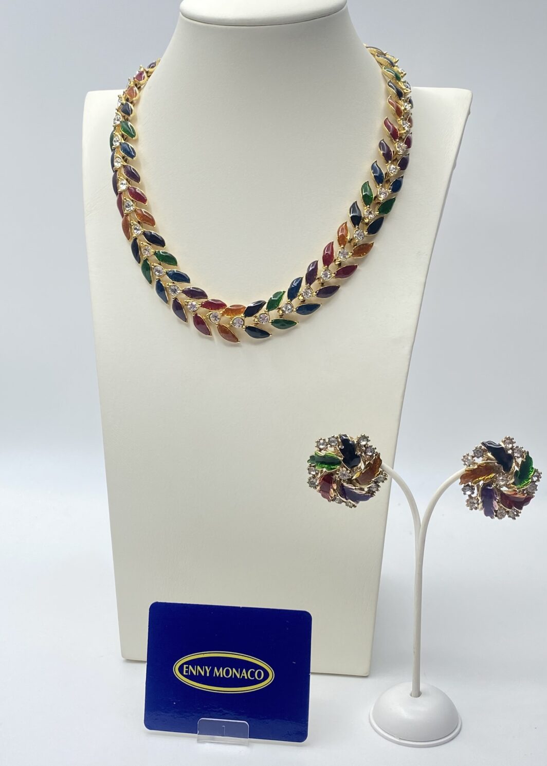 SPLENDIDA DEMI PARURE VINTAGE ENNY MONACO A MOTIVO FOGLIATO E SMALTI ARCOBALENO IN METALLO DORATO CON CRISTALLI APPLICATI – COLLIER GIROCOLLO E ORECCHINI BOTTONE COORDINATI, ANNI ‘80.