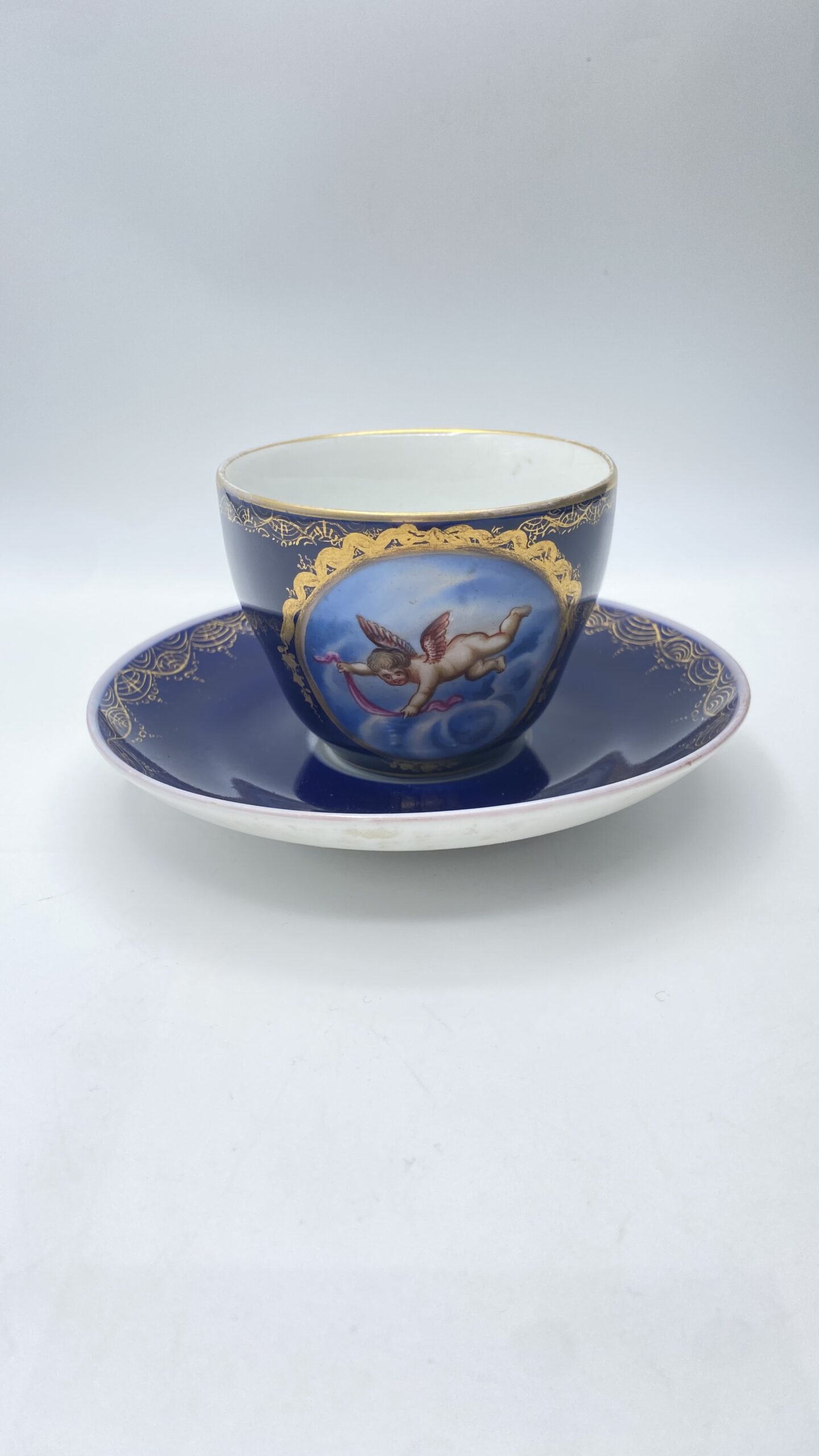 ECCEZIONALE TAZZA CON PIATTINO IN PORCELLANA BLU COBALTO, MEDAGLIONE CON PUTTO E ORO ZECCHINO – REALE MANIFATTURA KPM BERLINO, XVIII SECOLO.